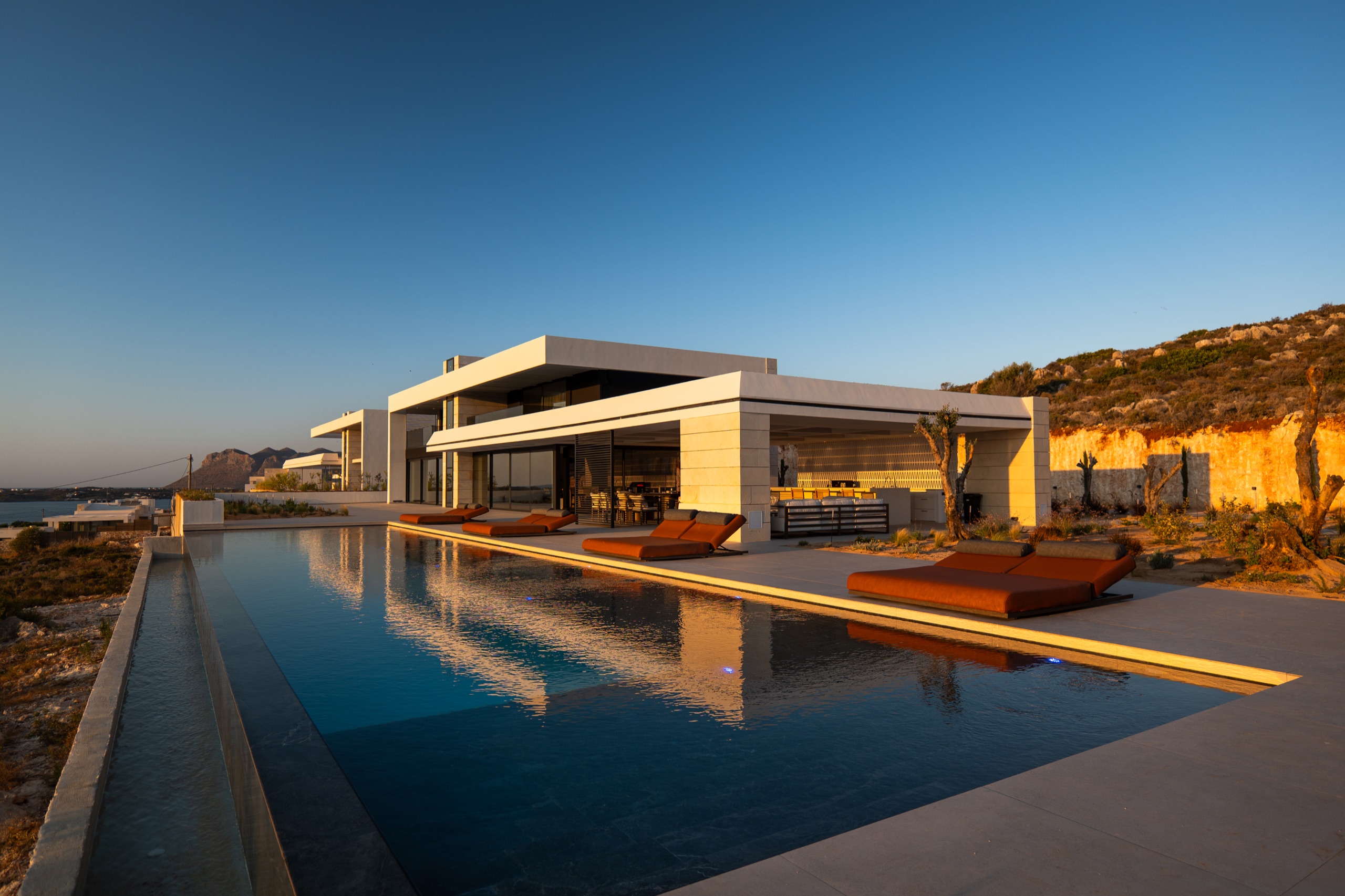 Villa KORA and its private infinity pool overlooking the coast at golden hour