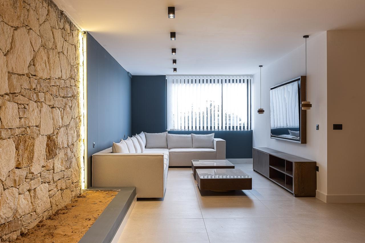 Deep lounge and second screen beside the raw stone wall